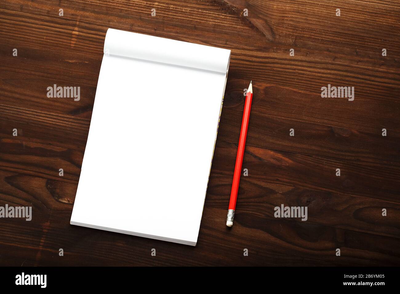 Notepad with red pencil on a brown wooden table background, for ...