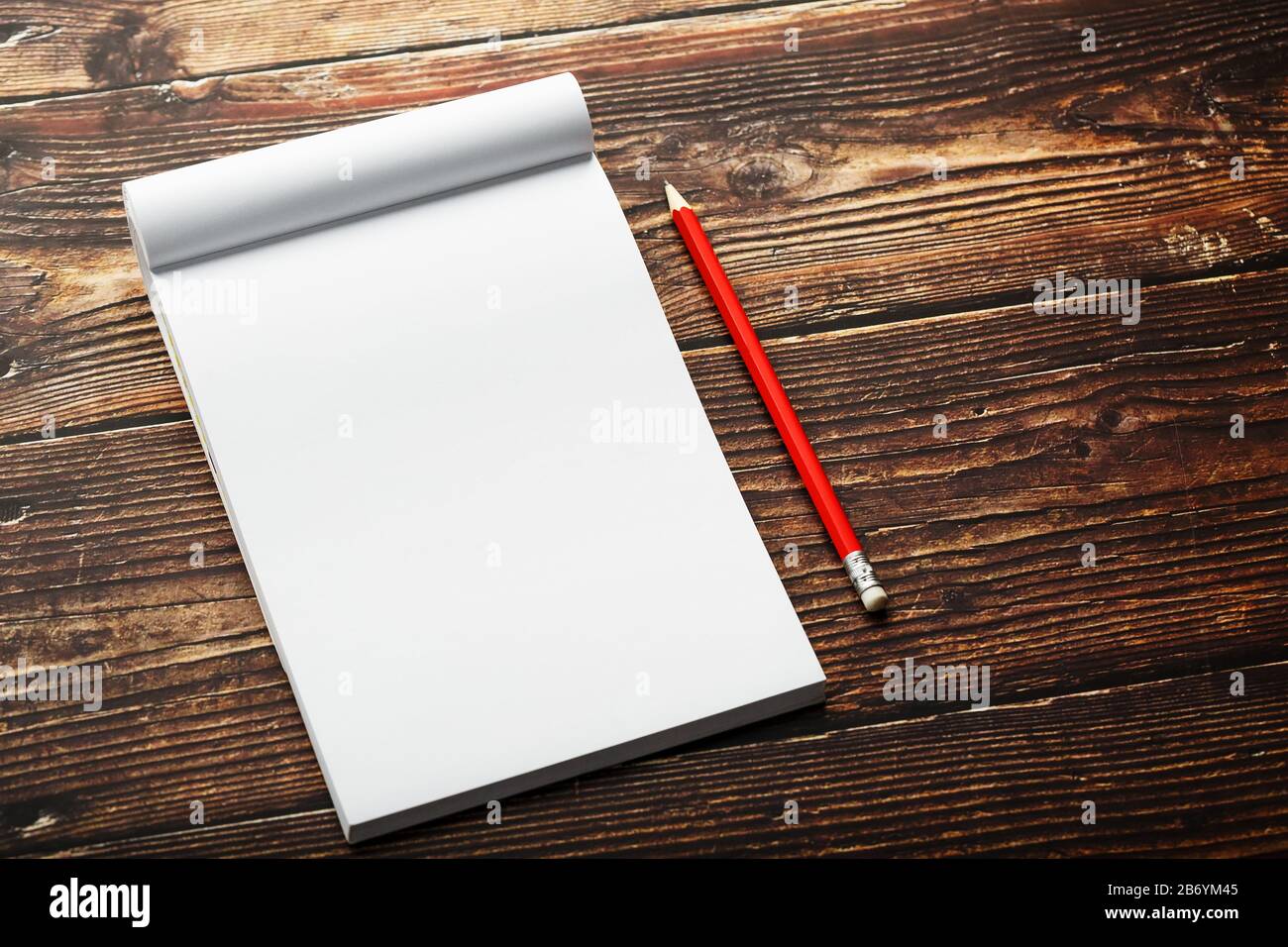 Notepad with red pencil on a brown wooden table background, for ...