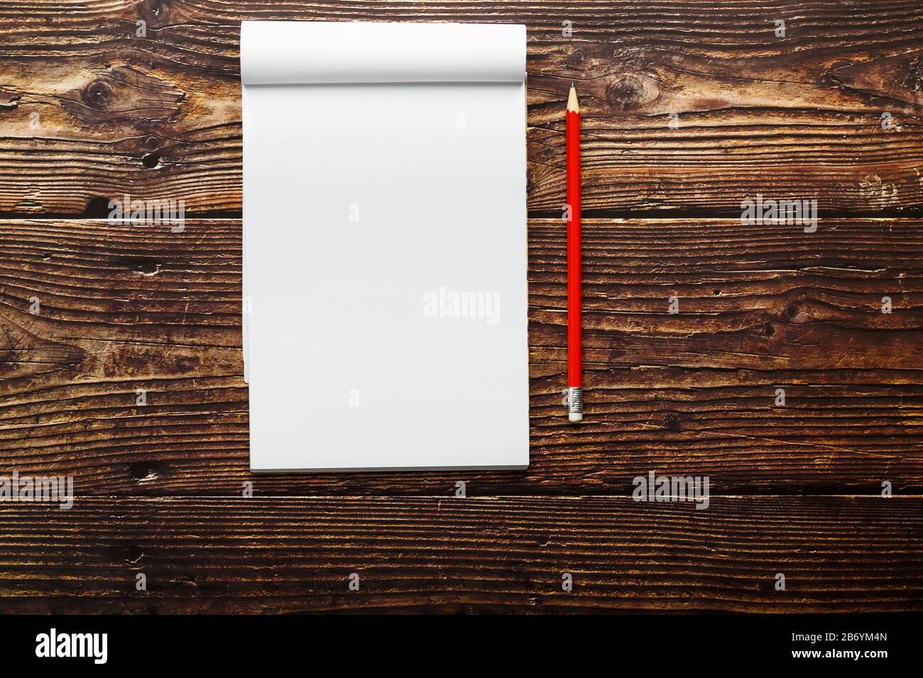 Notepad with red pencil on a brown wooden table background, for ...