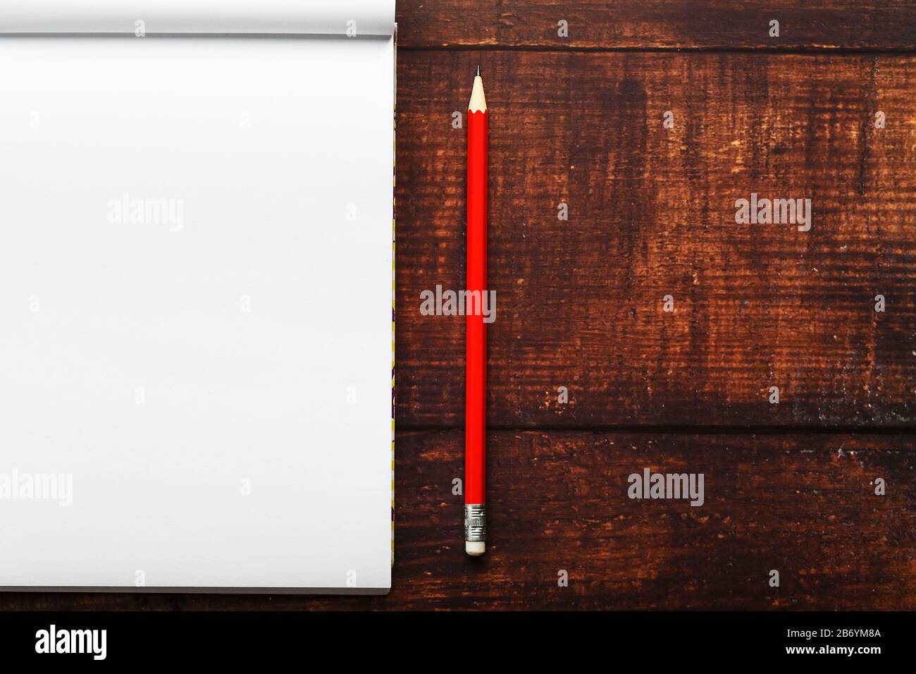 Notepad with red pencil on a brown wooden table background, for ...