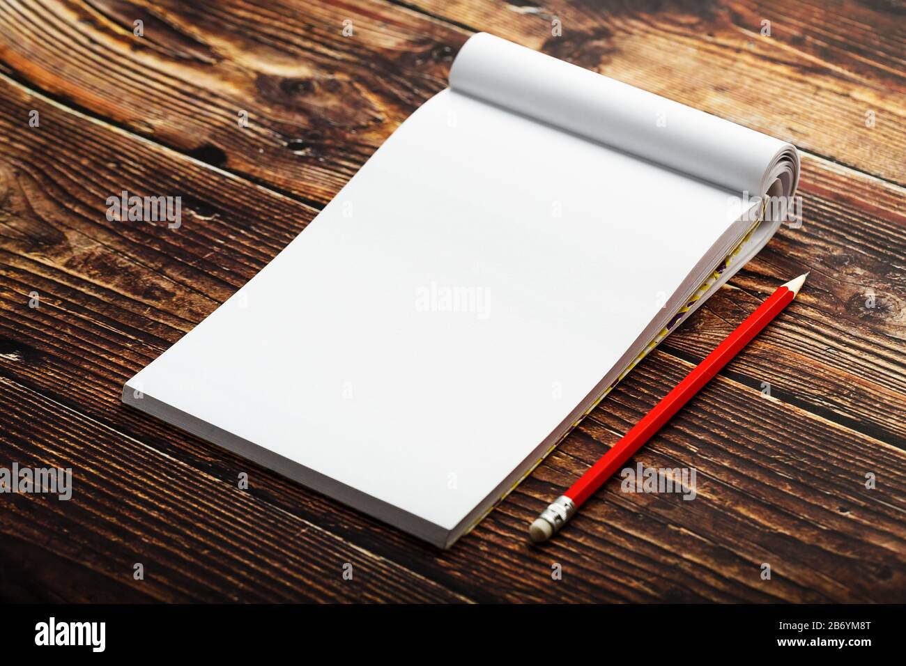 Notepad with red pencil on a brown wooden table background, for ...