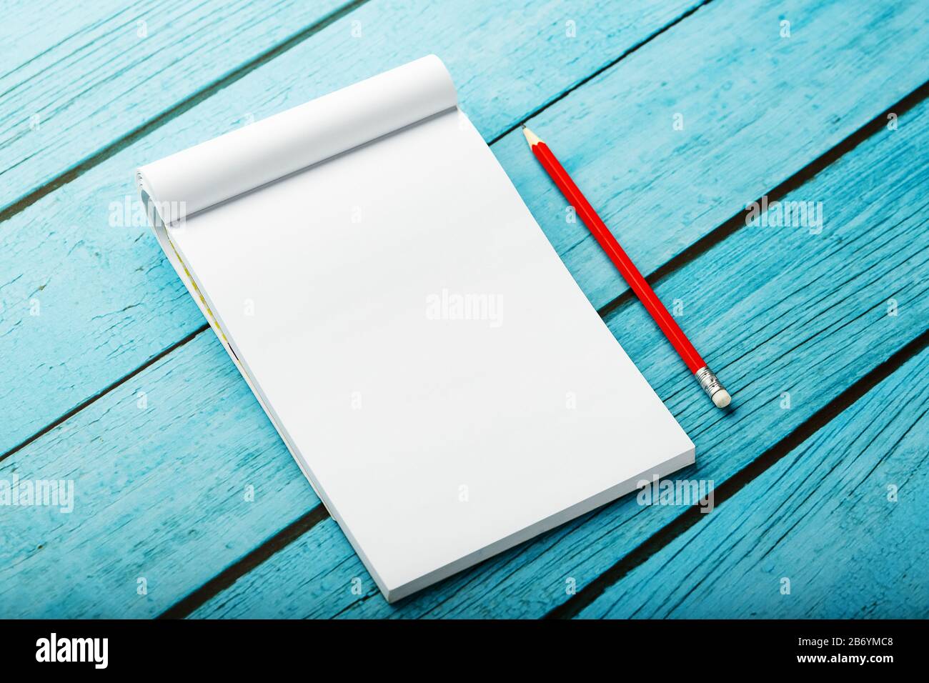 Notepad with red pencil on a blue wooden table background, for ...