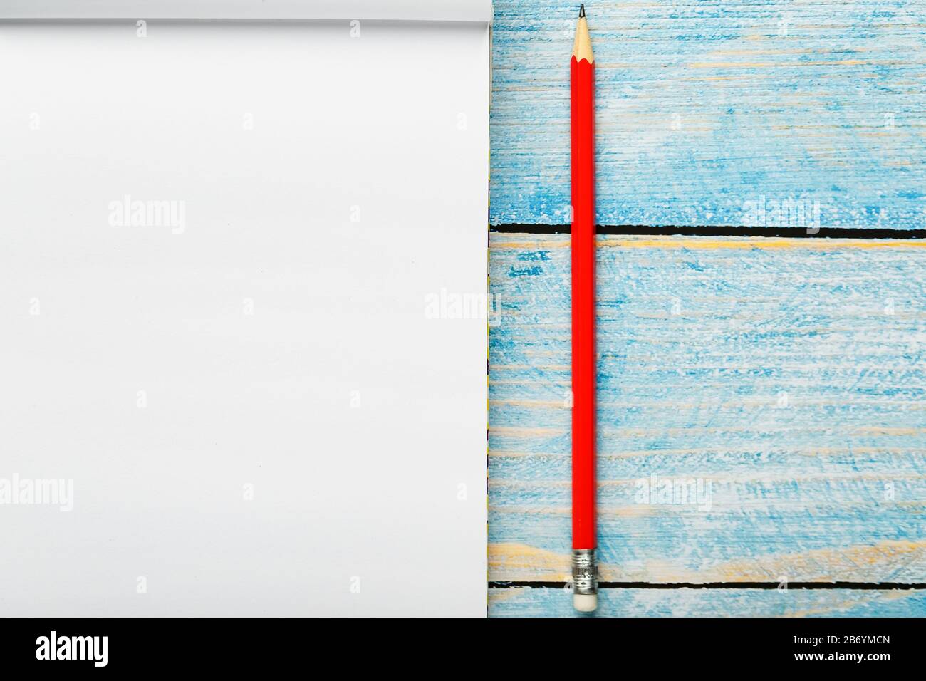 Notepad with red pencil on a blue wooden table background, for ...