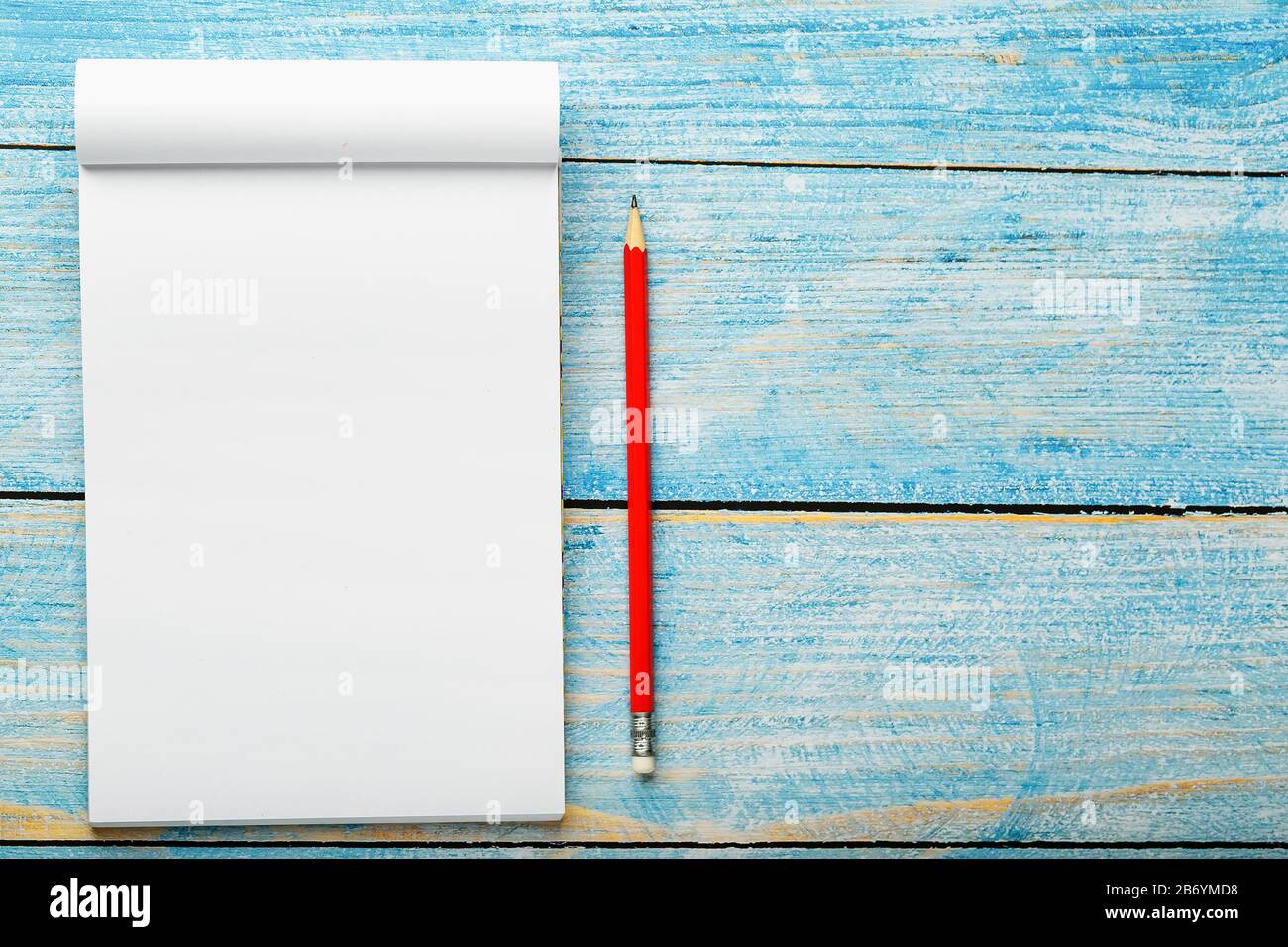 Notepad with red pencil on a blue wooden table background, for education,  write goals and deeds. Free white space for writing on a blank sheet of  note Stock Photo - Alamy