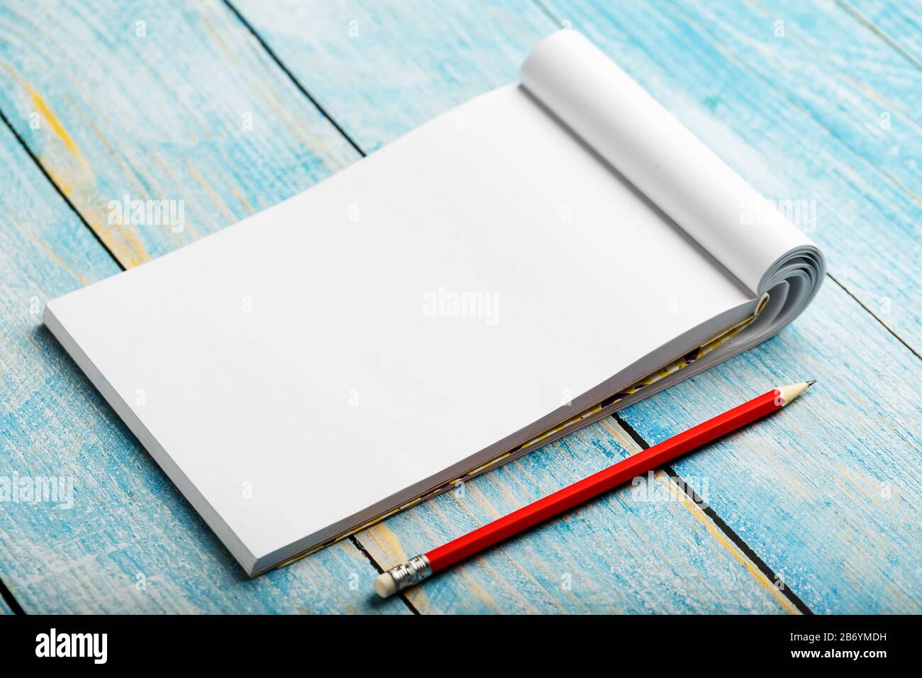 Notepad with red pencil on a blue wooden table background, for ...