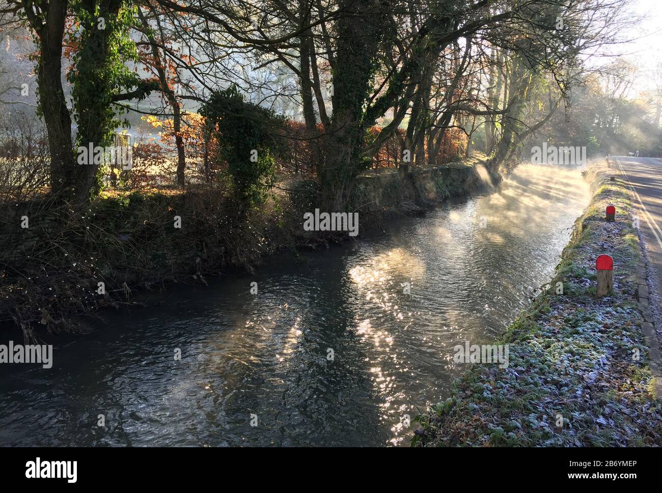 Country lane and stream bathed in low winter sunlight Stock Photo