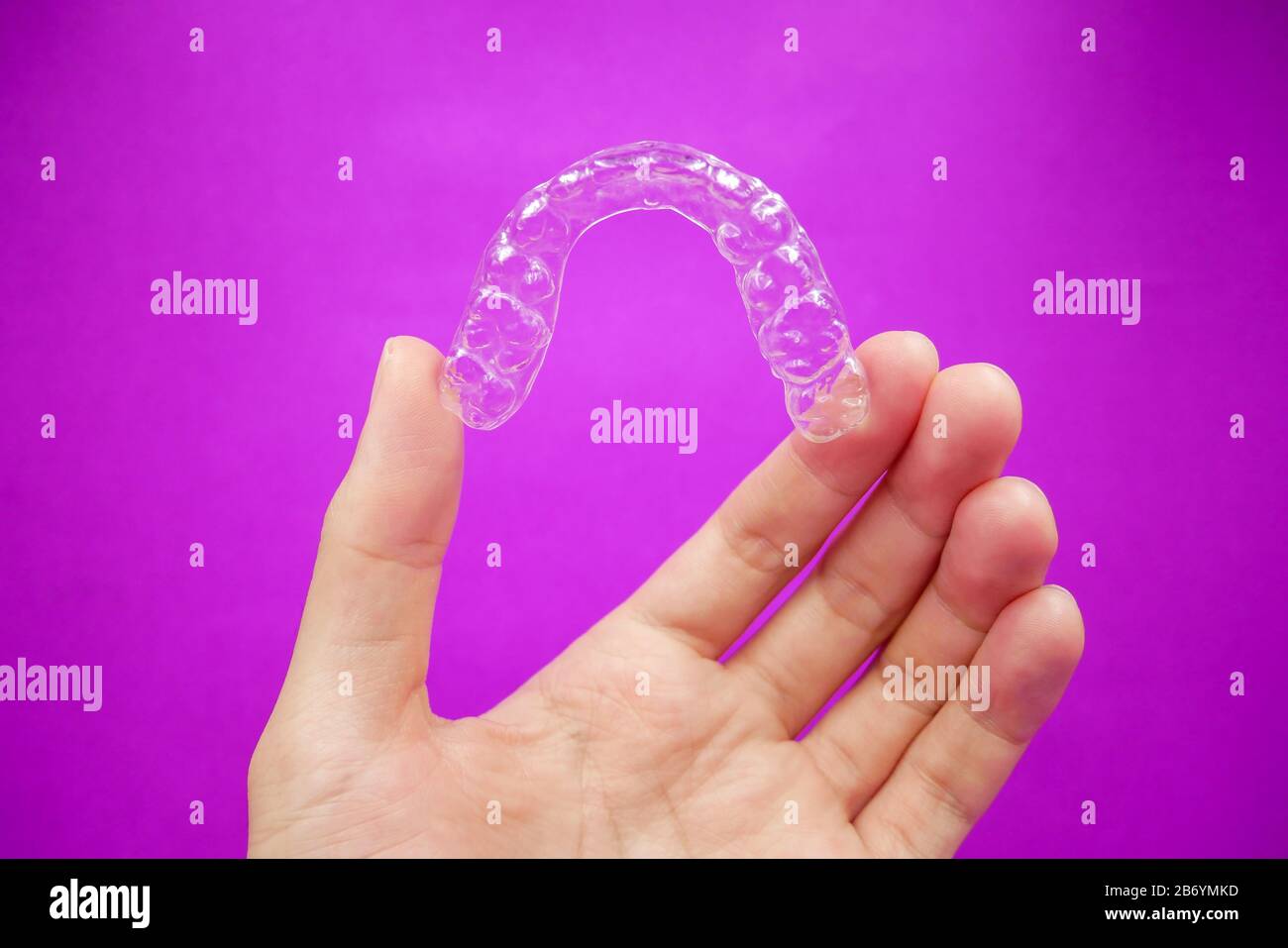 hand holding clear plastic retainer teeth that isolated on purple