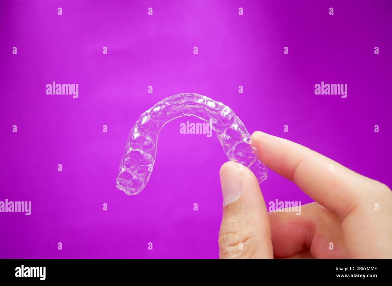 hand holding clear plastic retainer teeth that isolated on purple ...