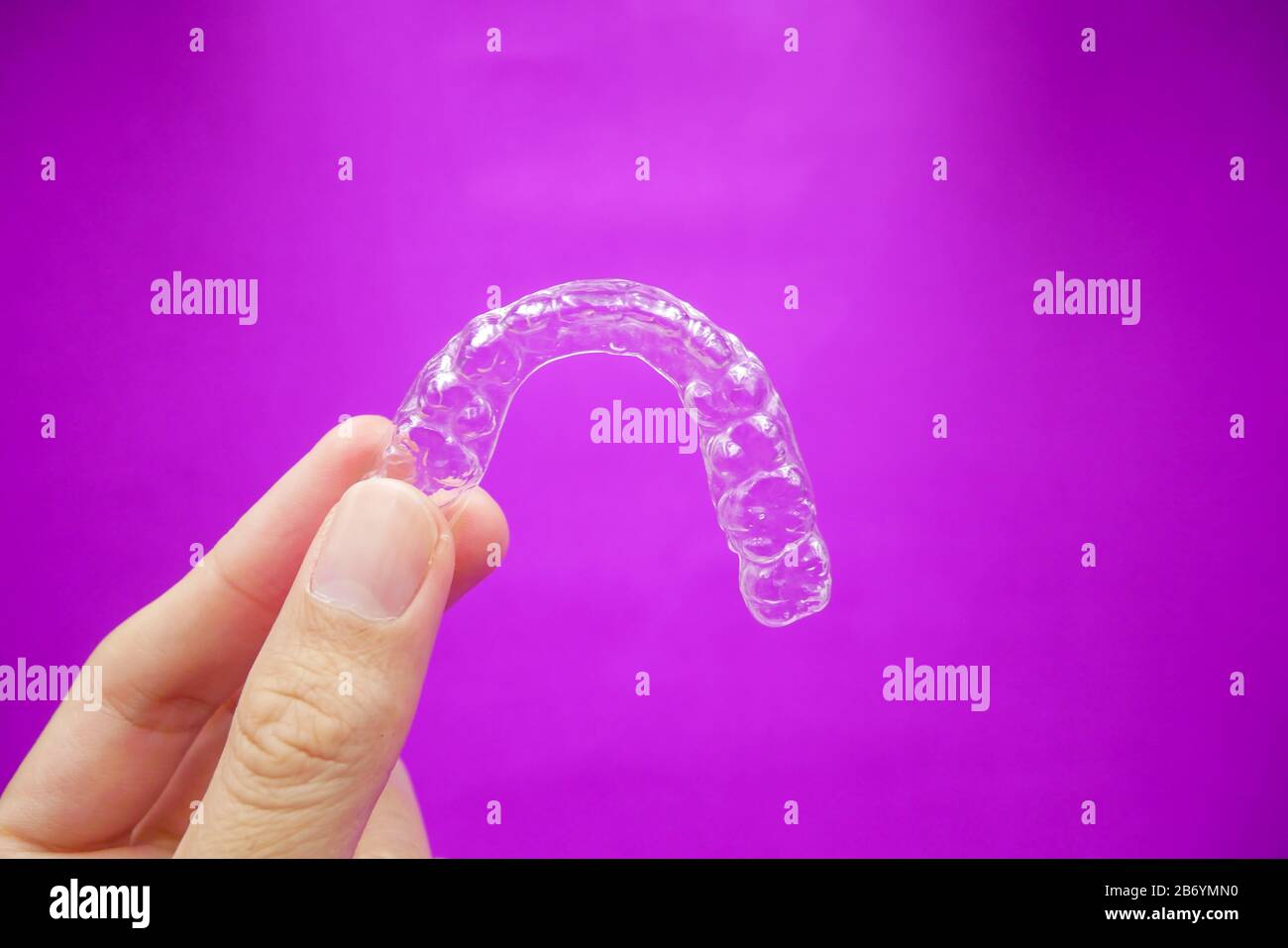hand holding clear plastic retainer teeth that isolated on purple