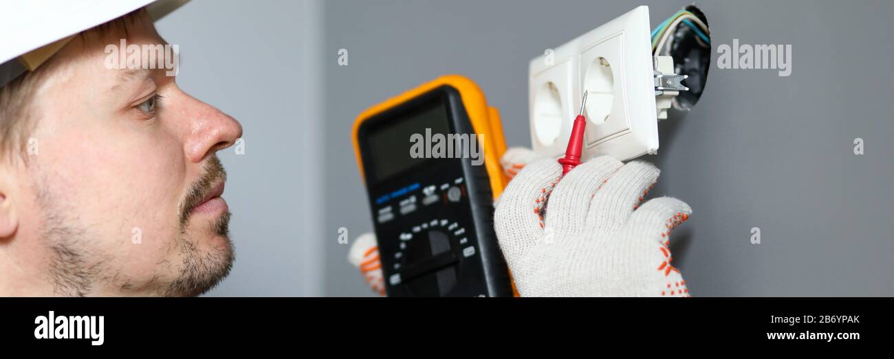 Electrician in helmet measures level electricity Stock Photo
