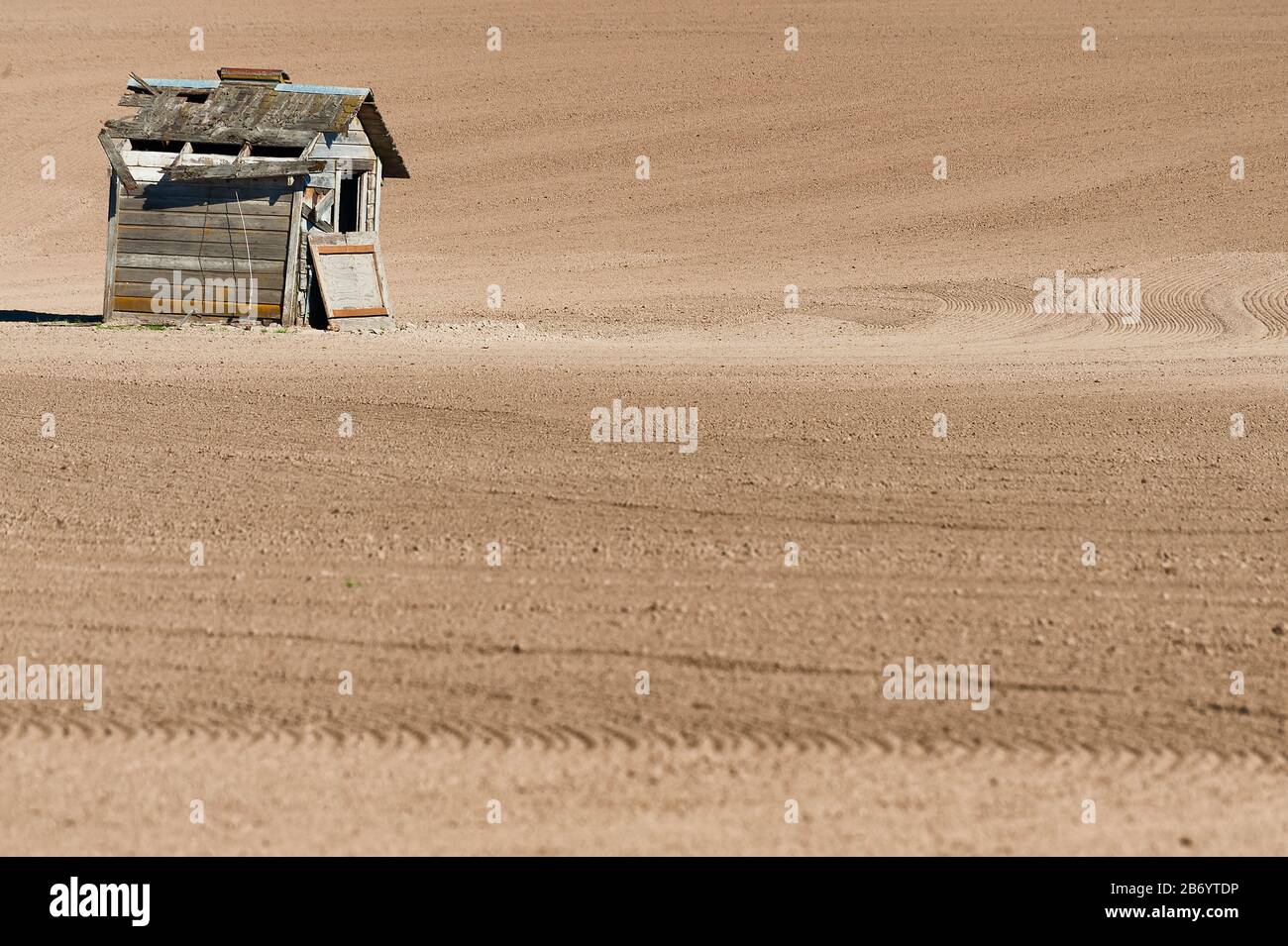 Freshly worked agricultural ground with a lone shack in this minimalist image. Stock Photo