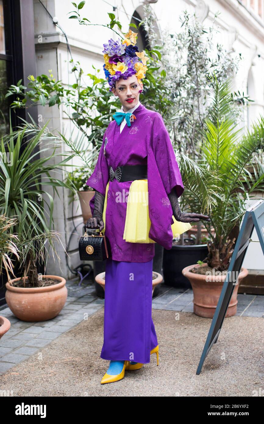 LONDON, UK- febryary 15 2020: Fashionable people on the street . Street style. A man in a purple kimono with a bright make-up and a crown made of yell Stock Photo