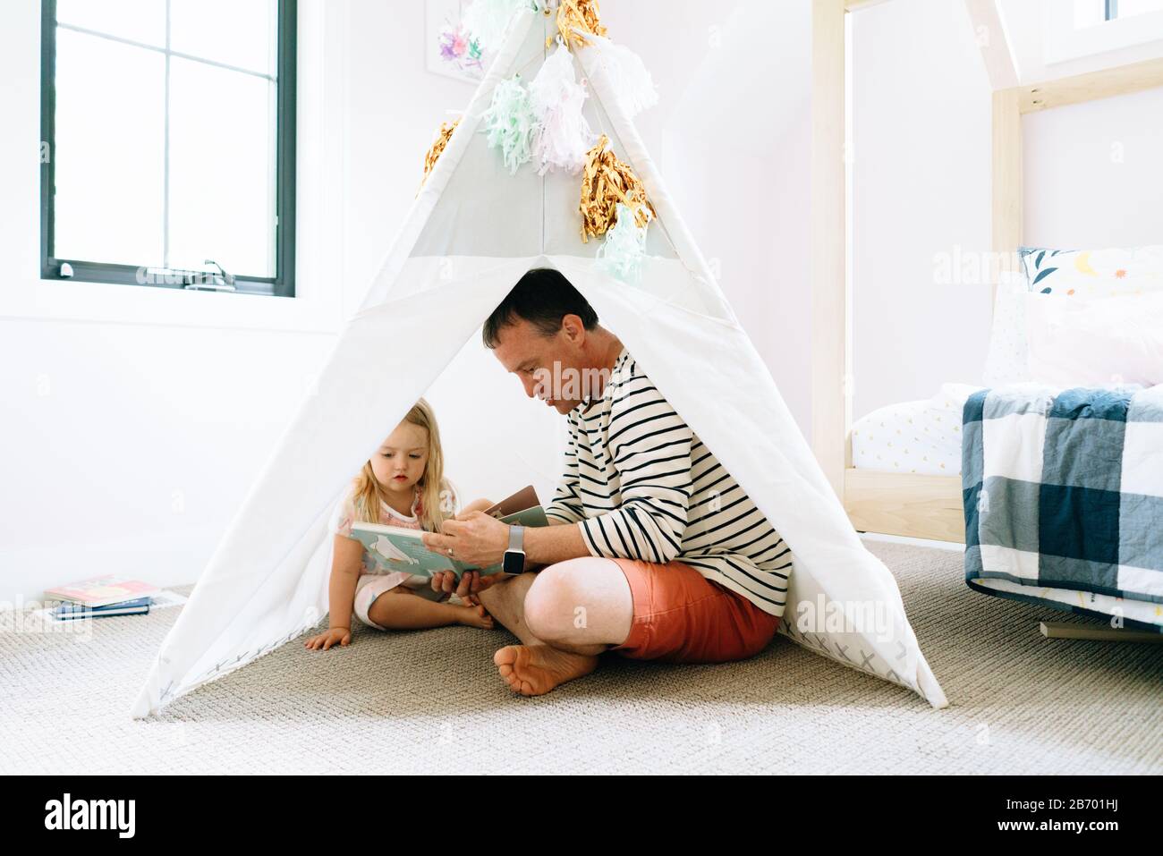 Closeup portrait of a dad and child reading together in a child's room Stock Photo