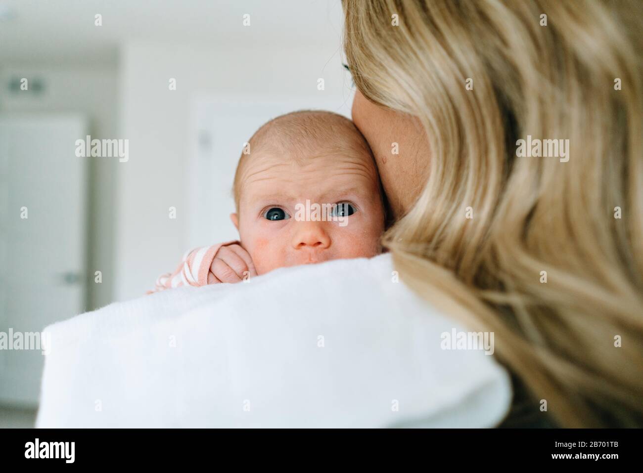 Over the shoulder view of a newborn baby girl being held by her mom Stock Photo