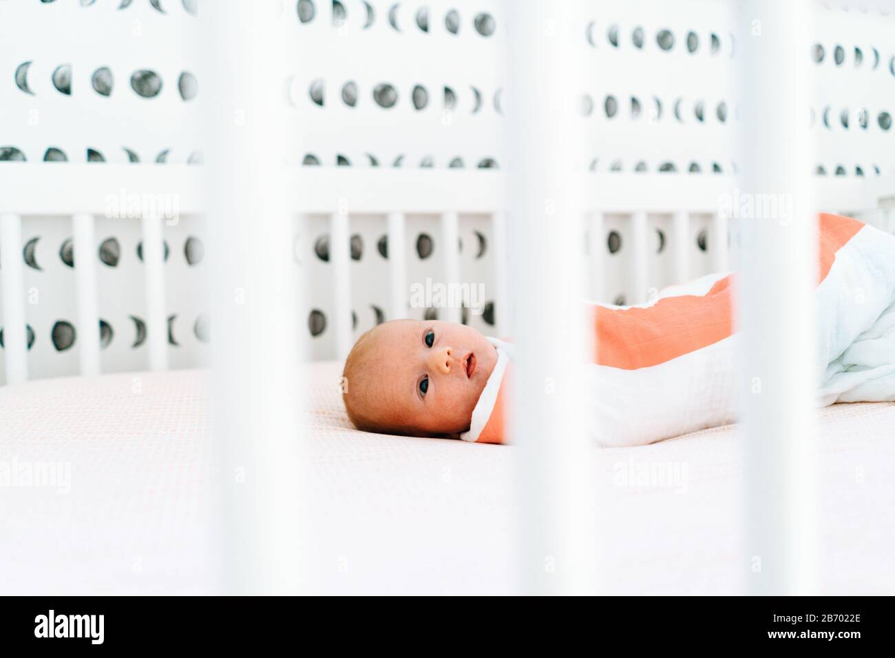 View through a crib of a newborn baby girl laying down Stock Photo
