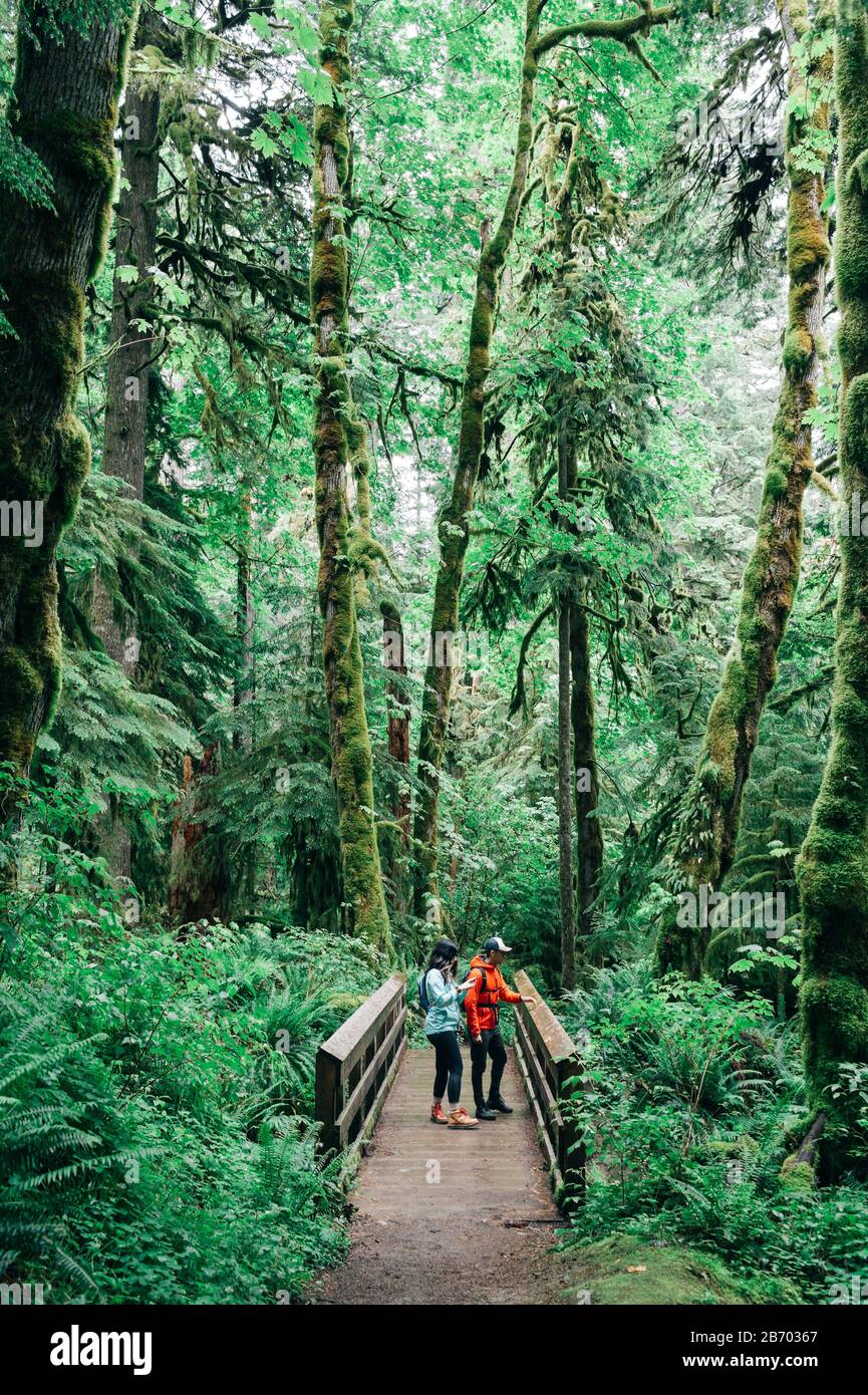 A young couple enjoys a hike on a bridge in the Pacific Northwest. Stock Photo