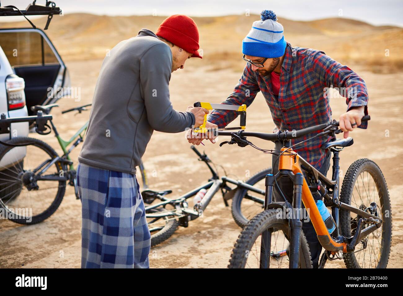 Two mountain bikers working together to modify handlebars. Stock Photo