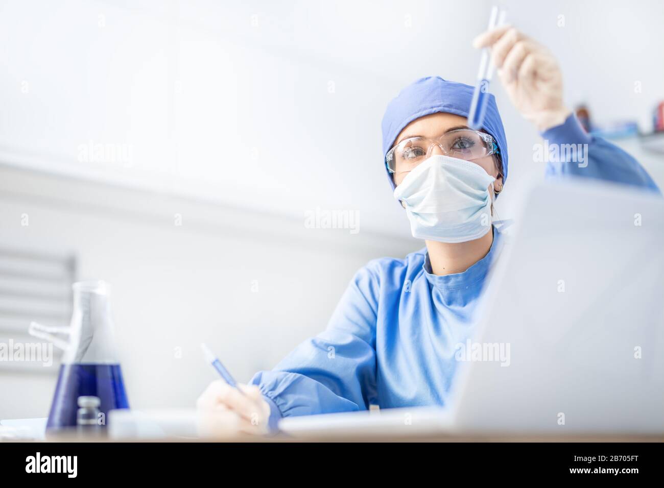 Female scientist or doctor specialist working in laboratory. Examines a substance in a test tube. Stock Photo