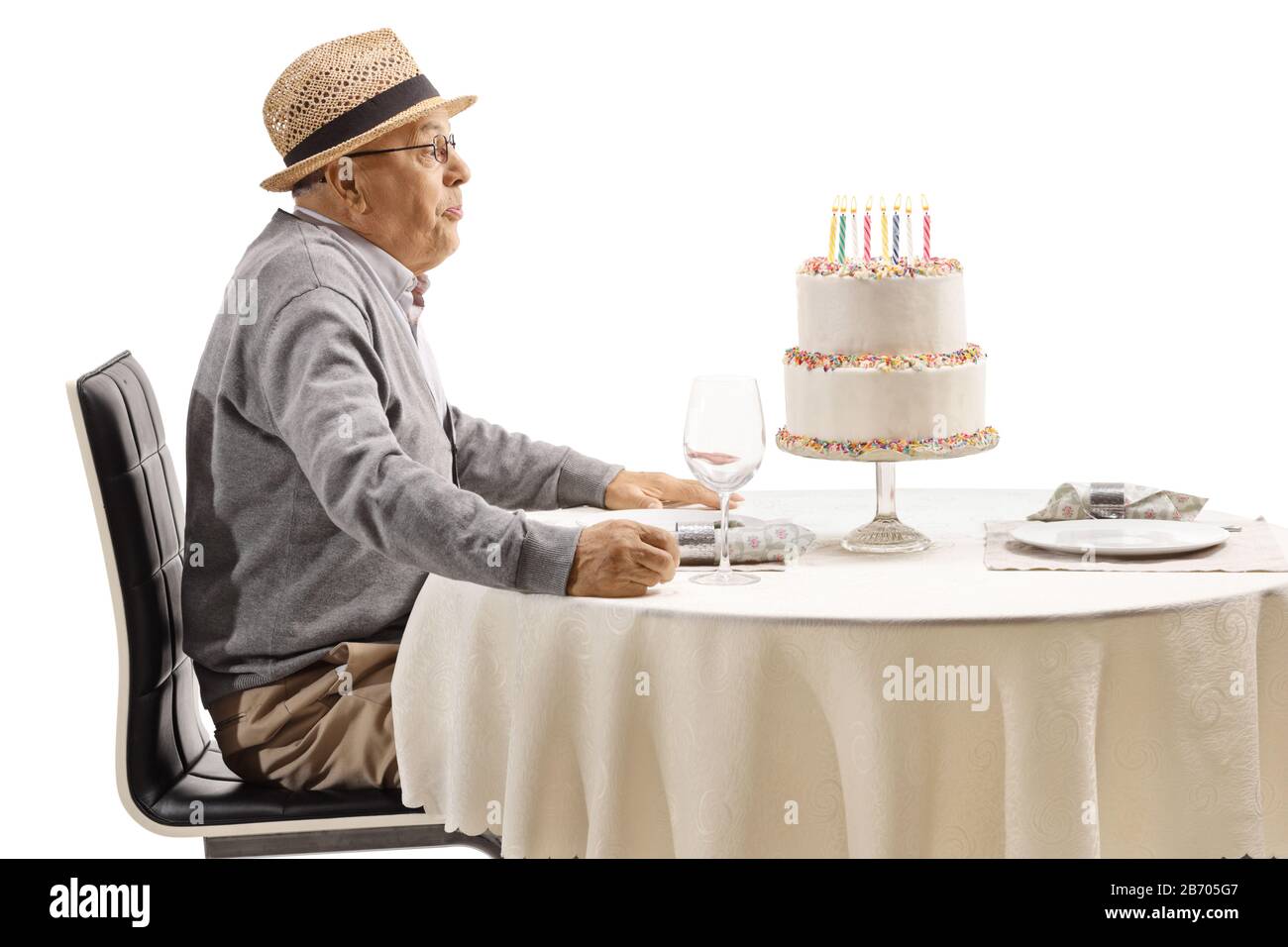 Elderly man blowing candles on a cake isolated on white background Stock Photo