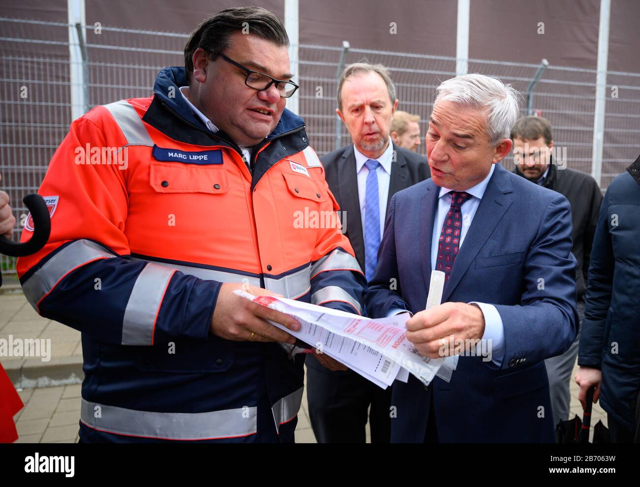 12 March 2020, Baden-Wuerttemberg, Stuttgart: Thomas Strobl (CDU, front, r), Minister of the Interior, Digitisation and Migration of Baden-Württemberg, listens to explanations of the procedure by Marc Lippe, District Managing Director of Malteser in the Neckar-Alb district, during a visit to a corona smear centre at the Stuttgart Trade Fair Centre. Photo: Sebastian Gollnow/dpa Stock Photo