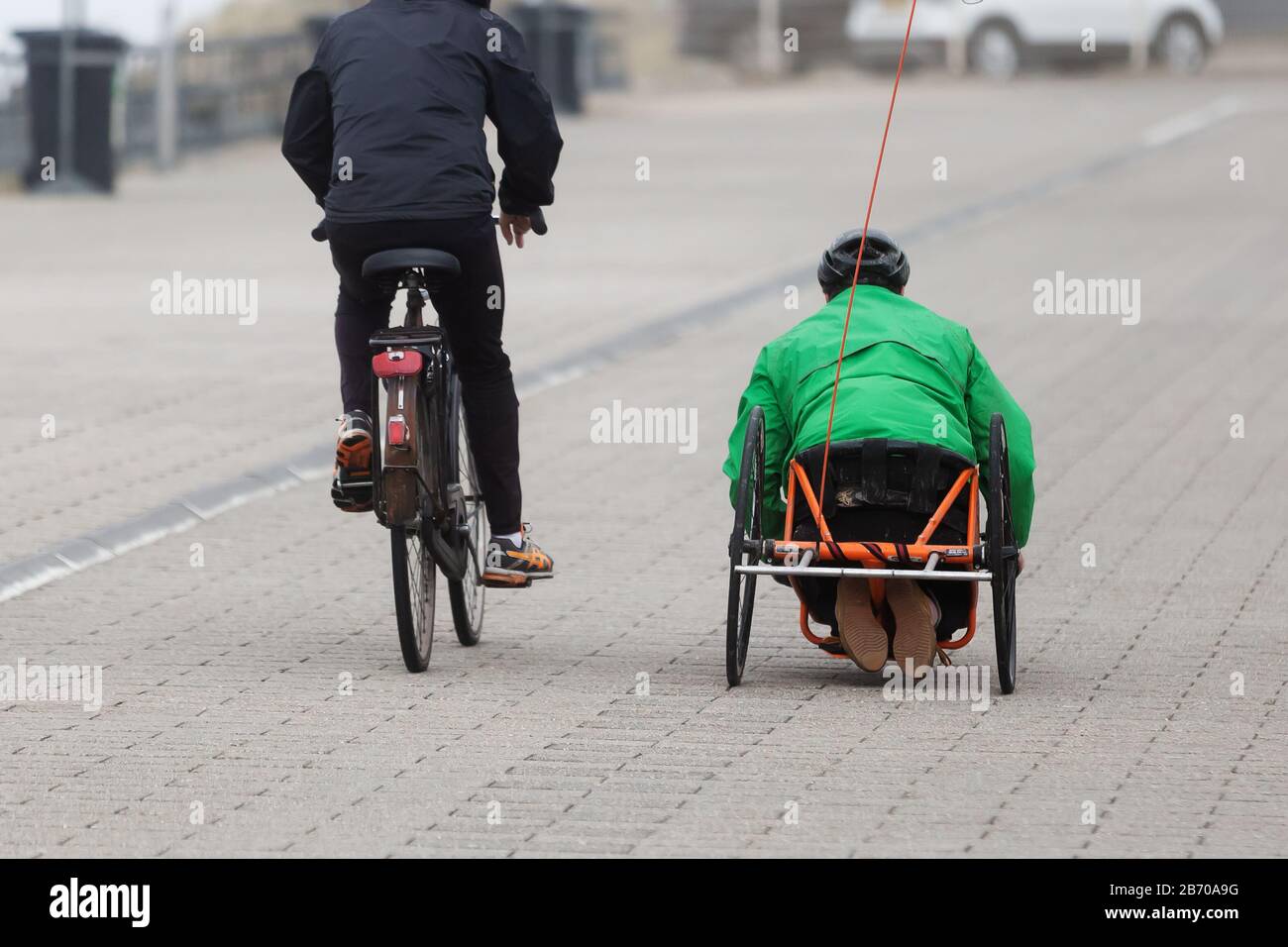 two unrecognizable persons with a bicycle and a recumbent cycle on a cycle path on a stormy day Stock Photo