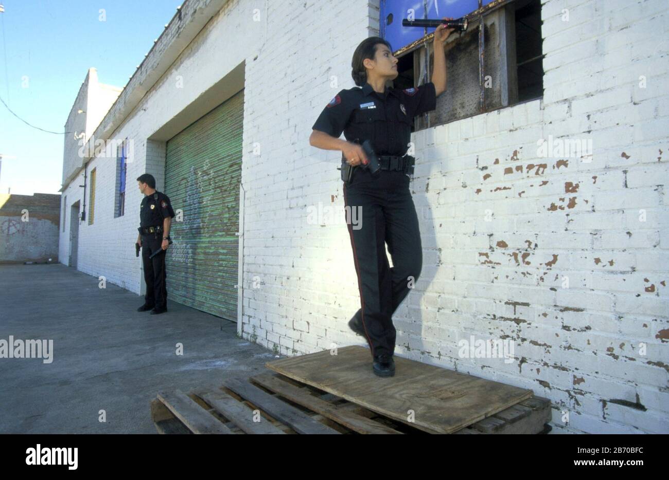 Austin Texas USA: Female police officer investigate broken window at warehouse.  MR * ©Bob Daemmrich Stock Photo