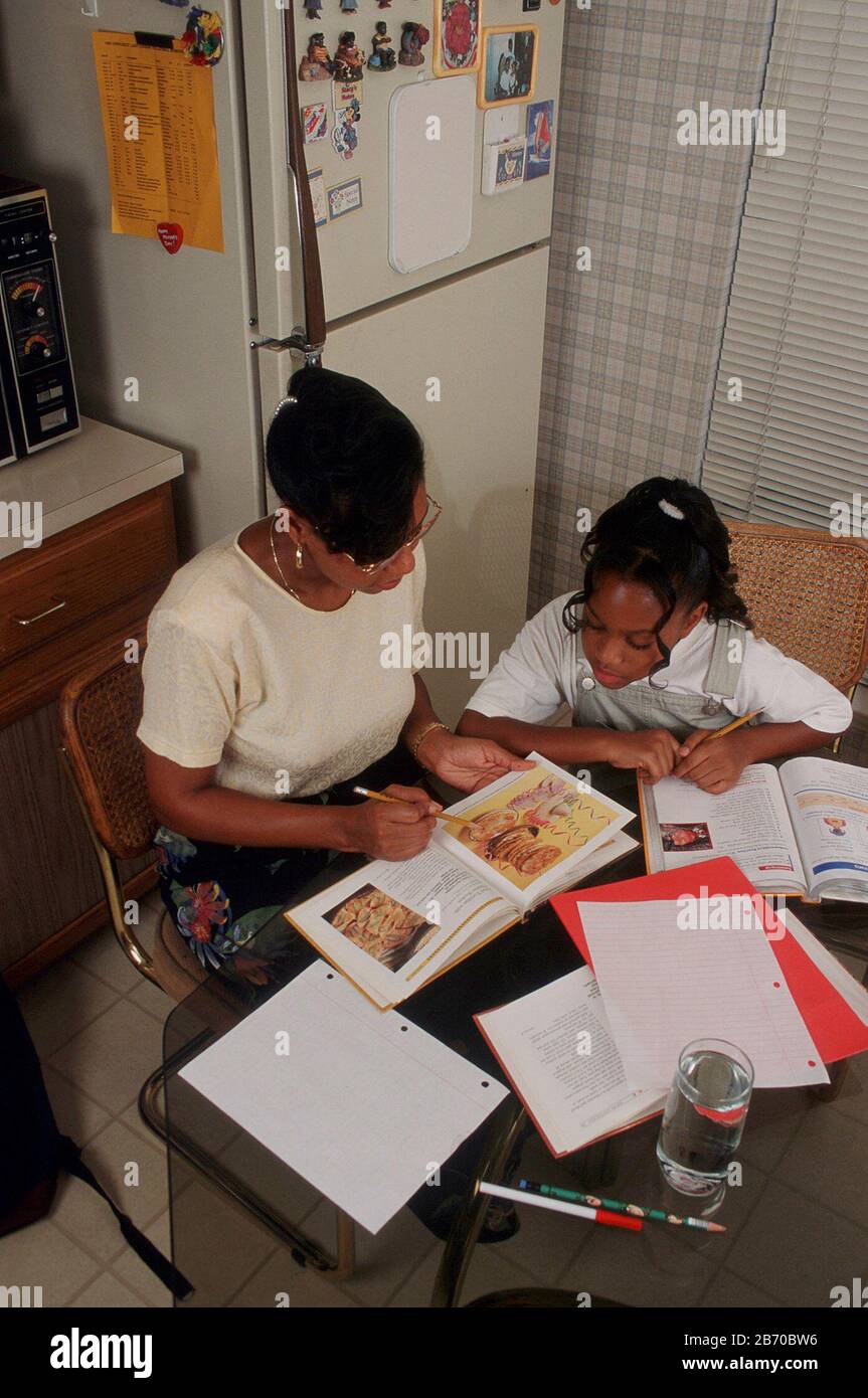 Mother and daughter looking at school textbook hi-res stock photography ...