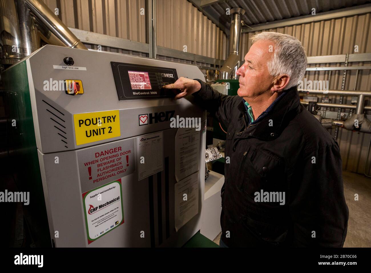 Poultry farmer Ronnie Wells stands beside his biomass boiler at his farm just outside Moira, Co. Down. The pellet boiler was purchased with the aid of the Northern Irish version of the Renewable Heat Incentive. A public inquiry into the Stormont government's botched handling of the scheme is due to publish its report tomorrow. Stock Photo