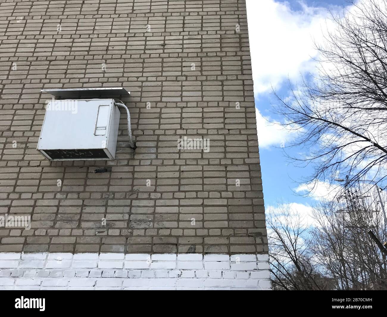 White air conditioning is hanging on the street, on a gray brick wall. On the corner of the building Stock Photo