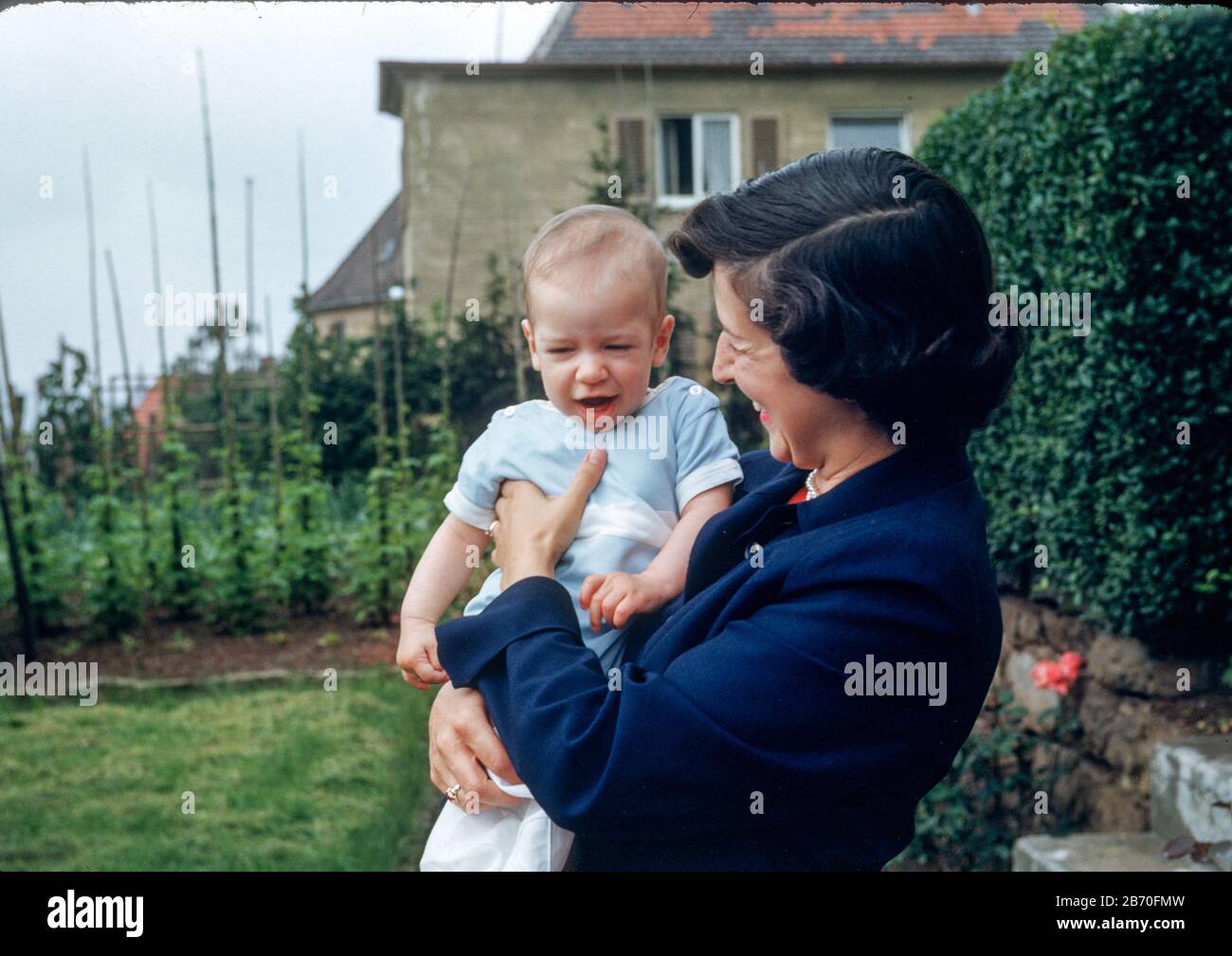 Young mother holds infant child in their backyard,  1950s Stock Photo