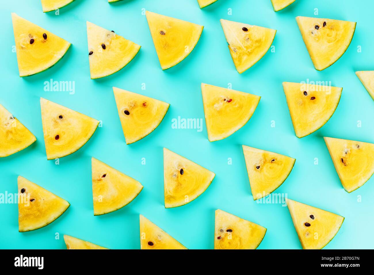 Pattern of slices of fresh yellow watermelon on a blue background. View ...