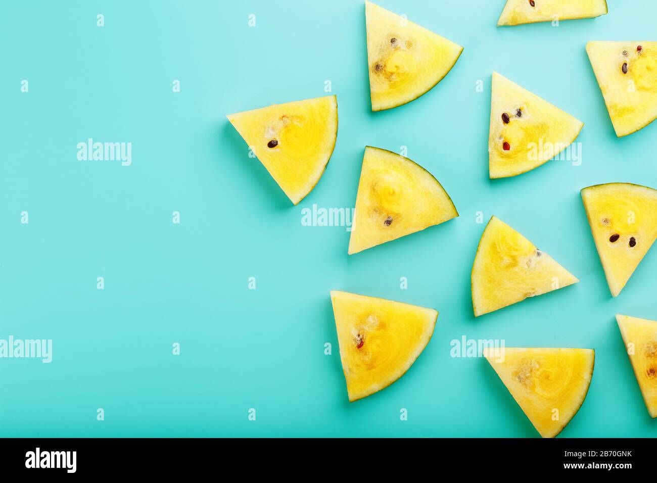 Pattern of slices of fresh yellow watermelon on a blue background. View ...