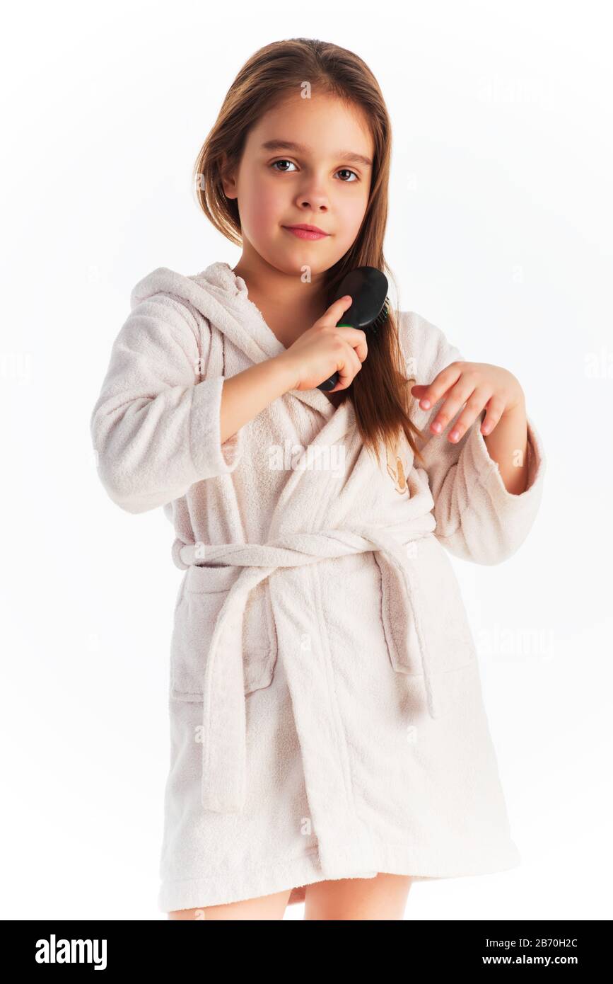 Little cute girl in a bathrobe combing hair posing on a white background in  the studio. Concept of taking care of young children. Advertising space  Stock Photo - Alamy