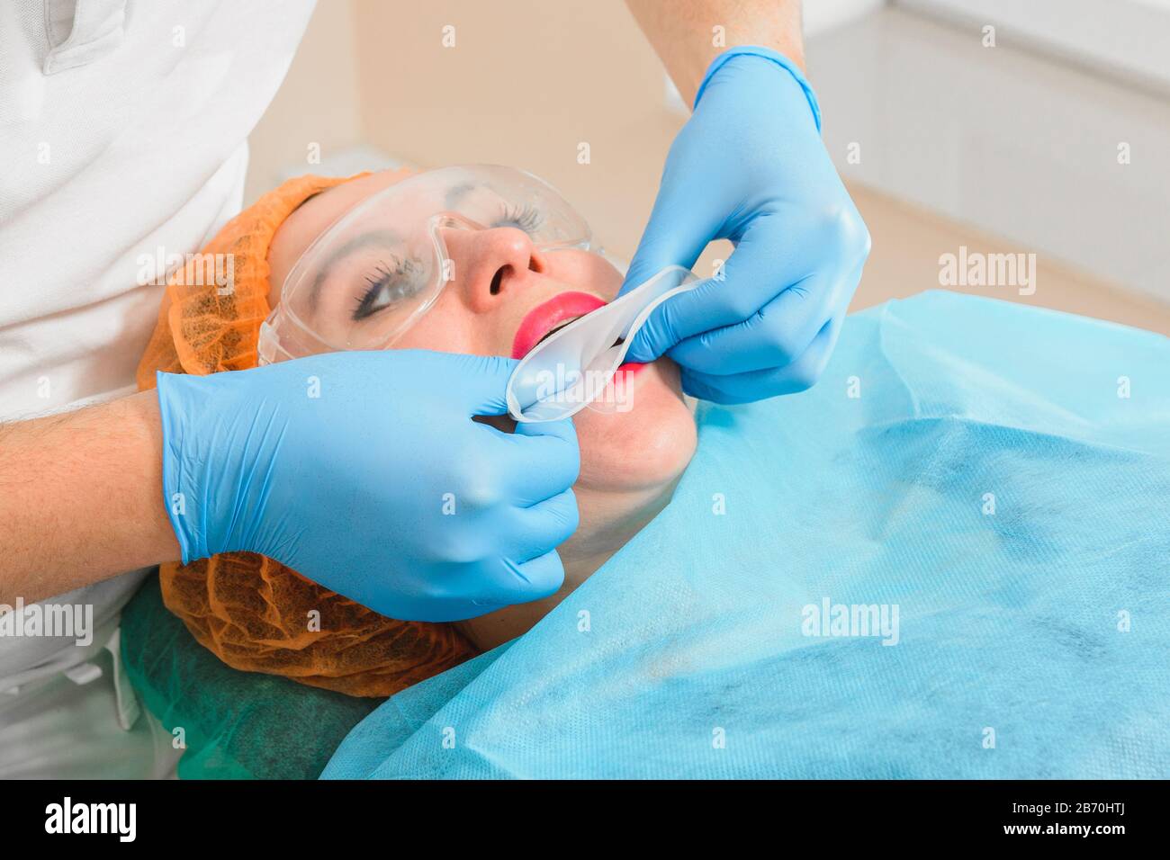 A young female dentist pulls a mouth extender at a dental clinic. 2020