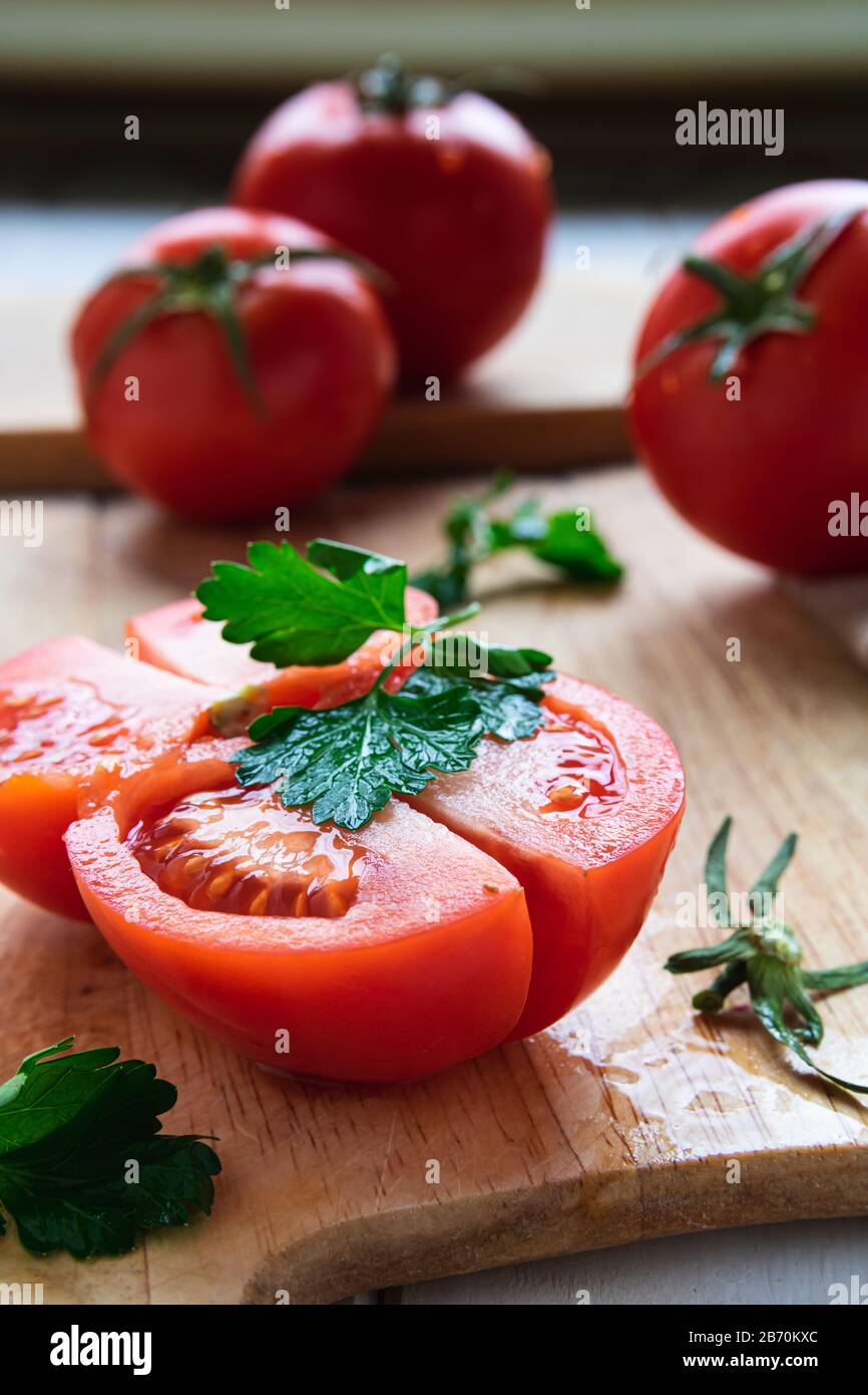 ripe tomatoes on a wooden board with parsley closeup Stock Photo