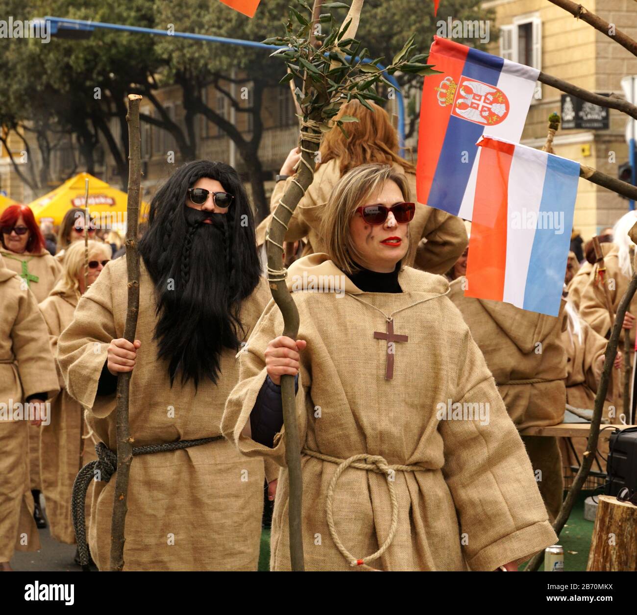 Rijeka, Croatia, February 23rd, 2020. Man and woman masked as a medieval priests costumes and dressed in jute dresses with large crucifix on the chest Stock Photo