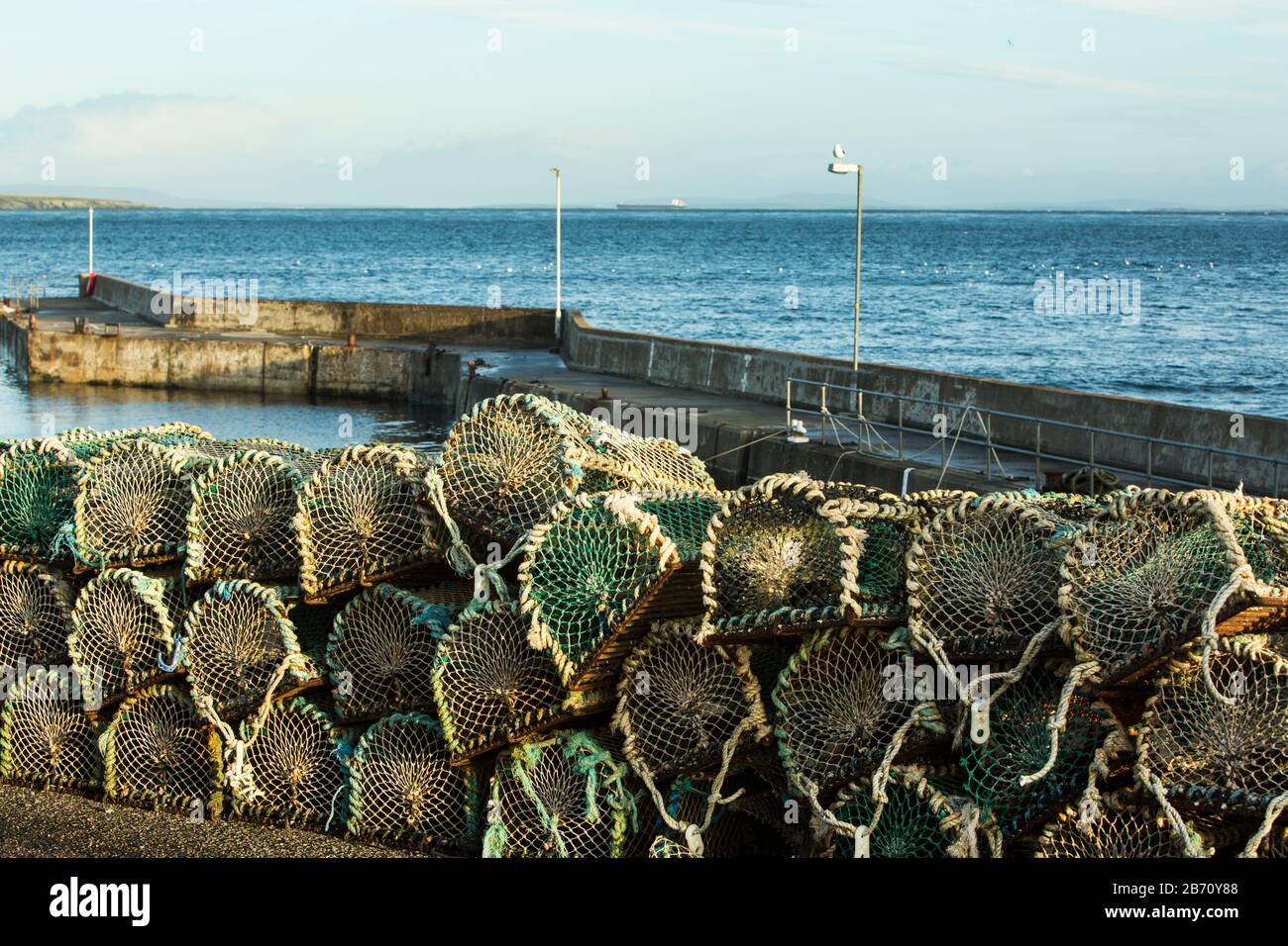 Lobster and crab pots stacked on the quayside harbour wall at John O'Groats, Caithness, Scotland, UK Stock Photo