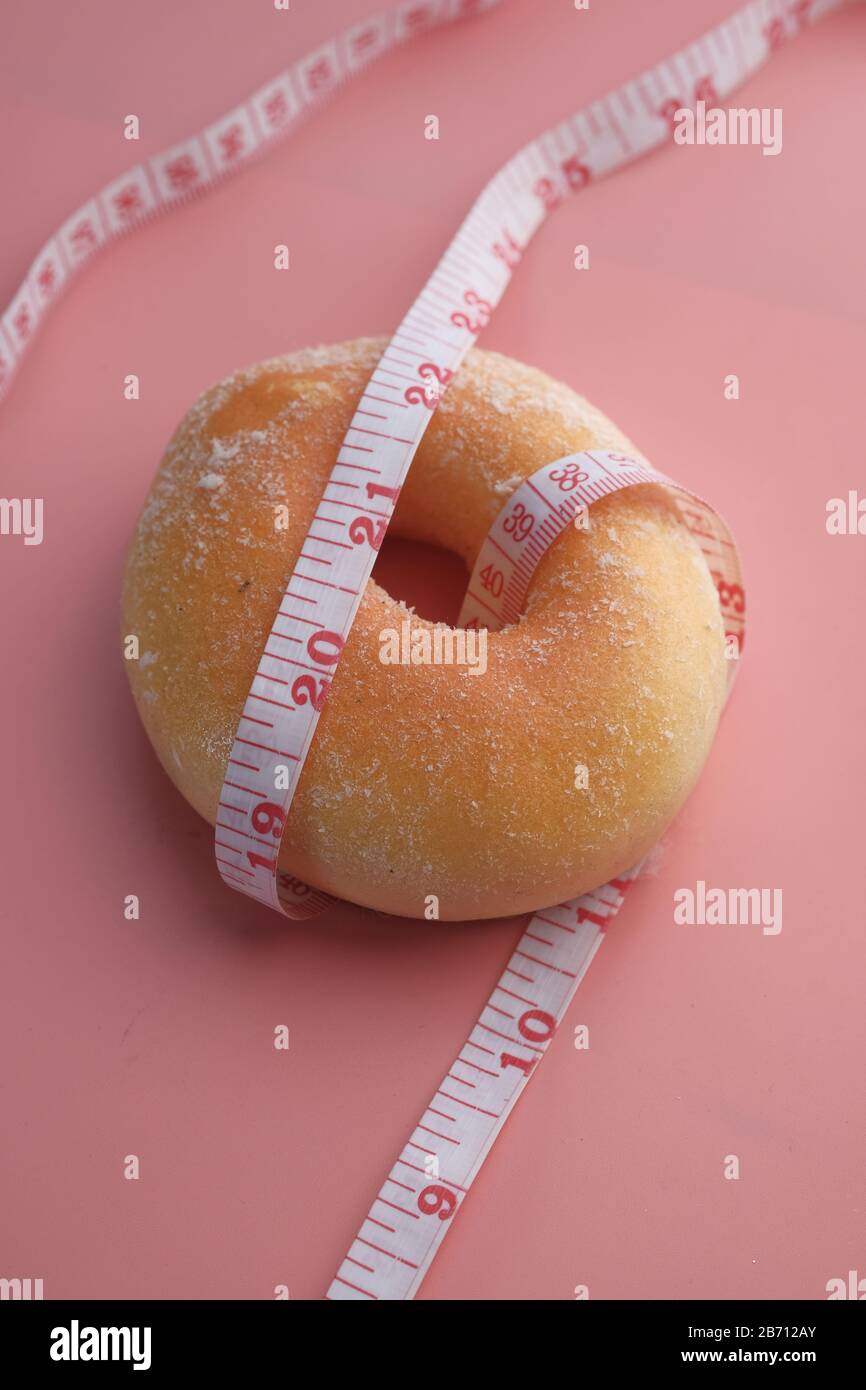 close up of measurement tape and donuts on pink background  Stock Photo