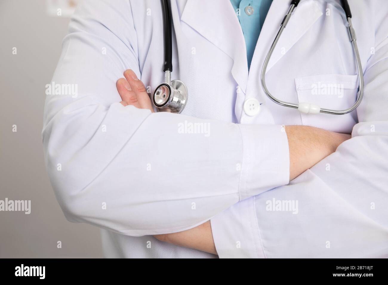 Male Doctor Standing With Arms Crossed In Clinic Stock Photo