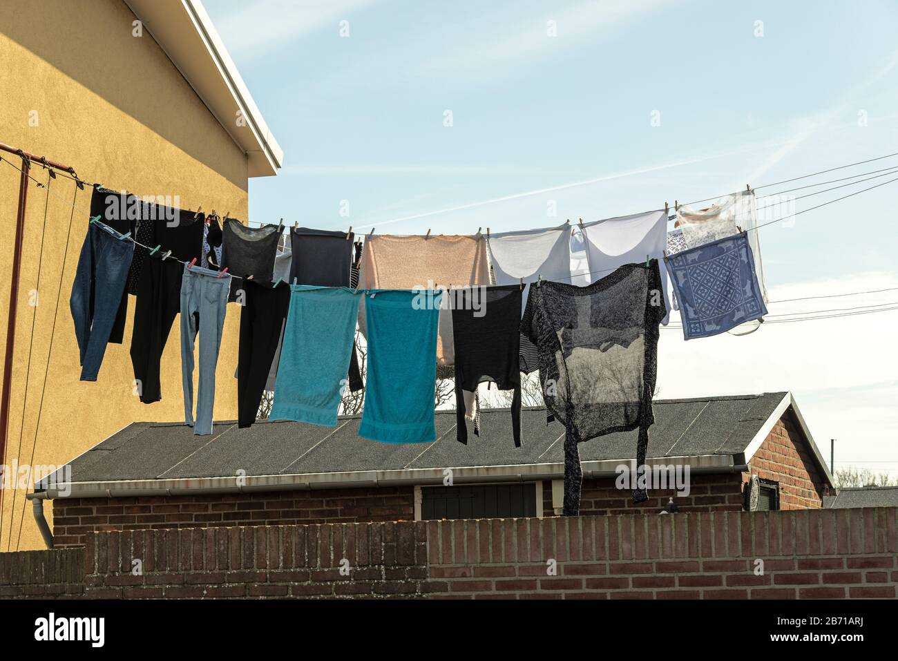 various laundry items in various colors hang outside on the washing line Stock Photo