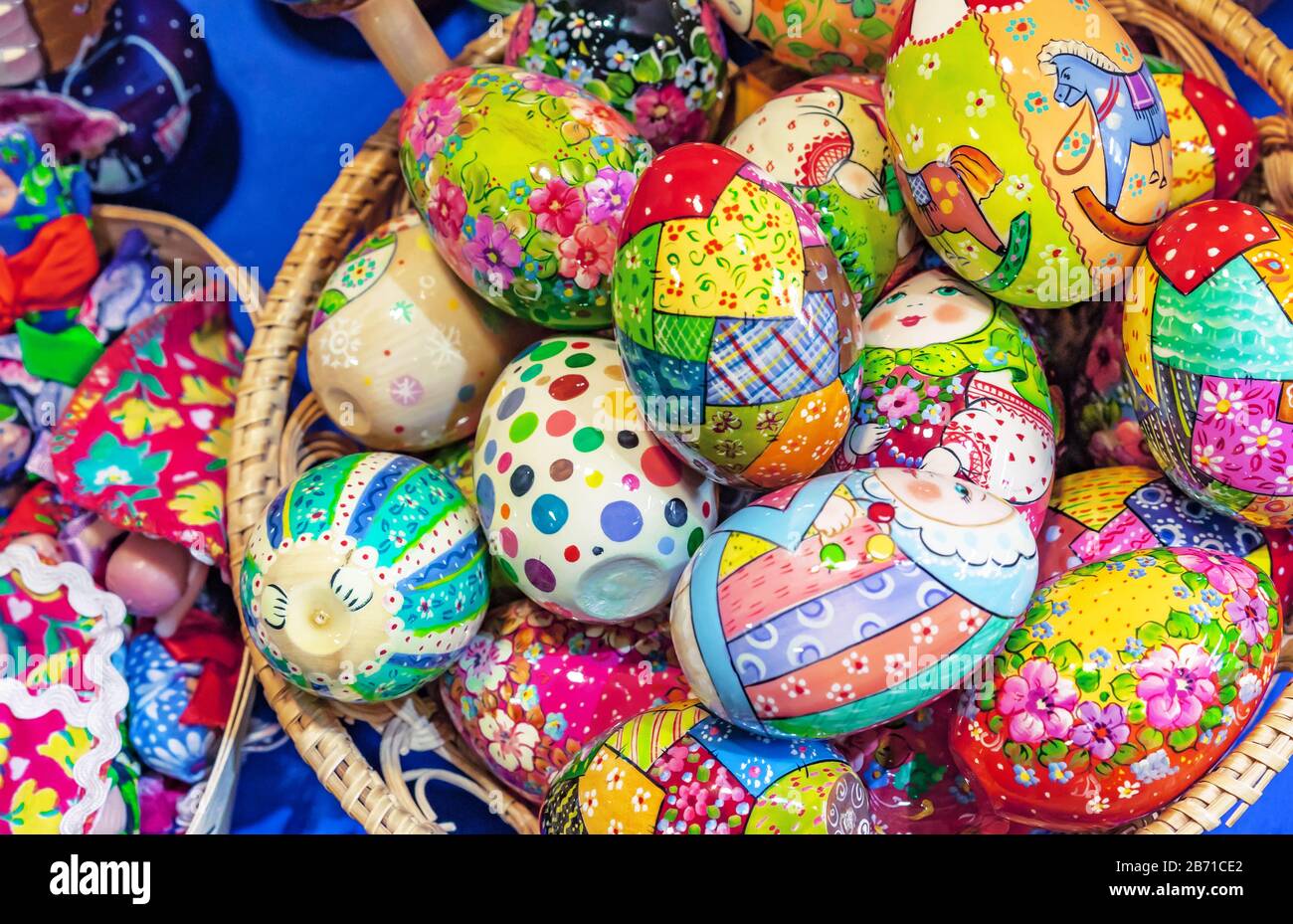 Wooden Easter eggs with bright drawings lie in a wicker basket. Stock Photo