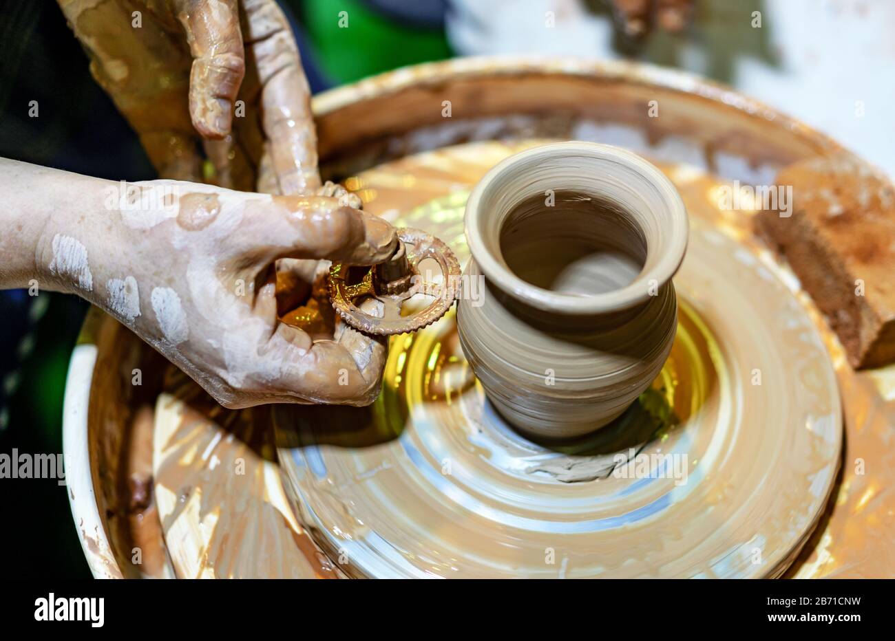 Professional potter makes a pot on a pottery wheel. Hands of a potter. Stock Photo