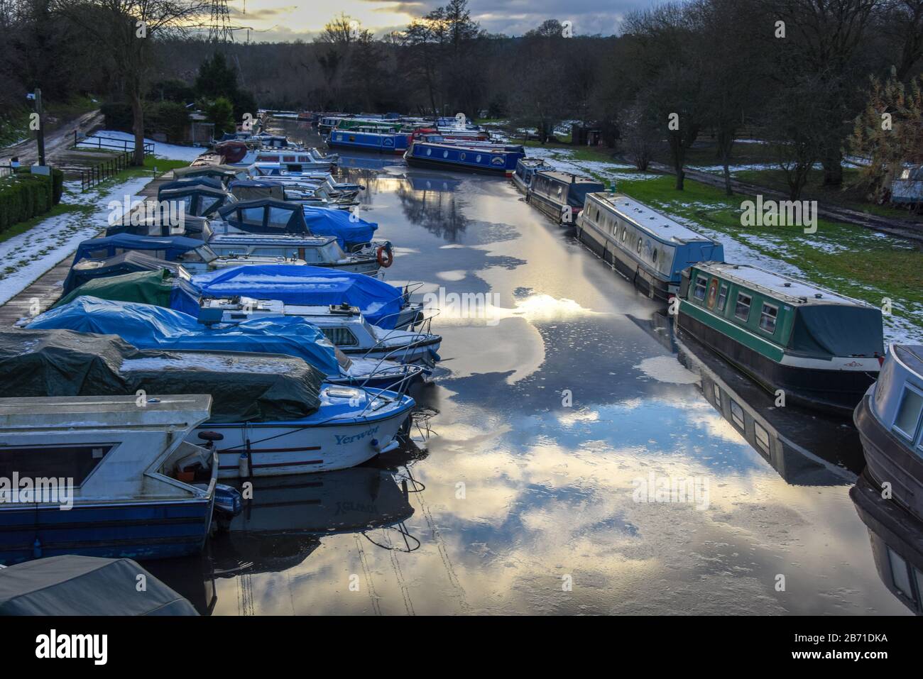 Looking down onto a number of moored boats on a cold winters day in an inland marina with partly frozen water UK. Stock Photo