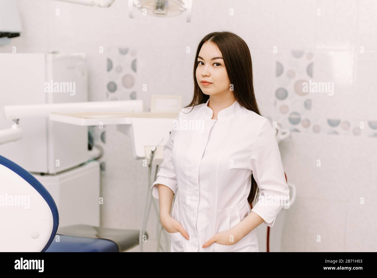 cheerful female dentist smiling in her office. dentistry student standing in a dental treatment room. Stock Photo