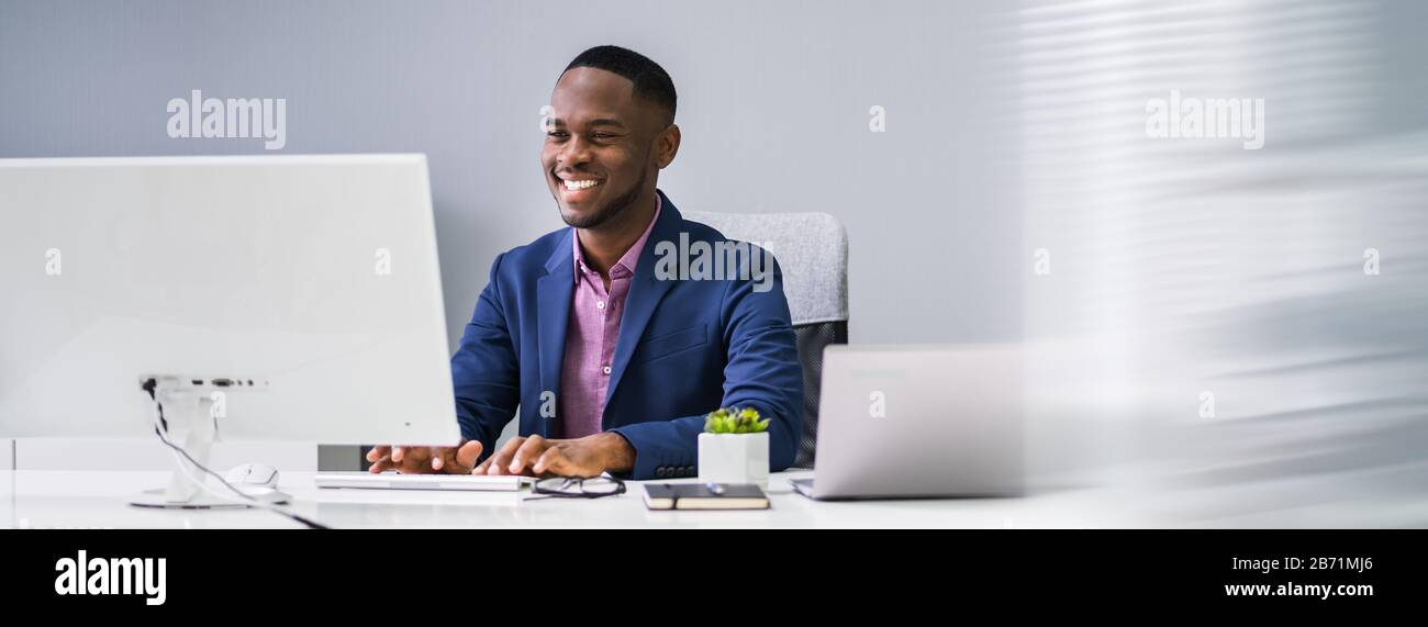African Businessman Banner Using Computer In Office Stock Photo