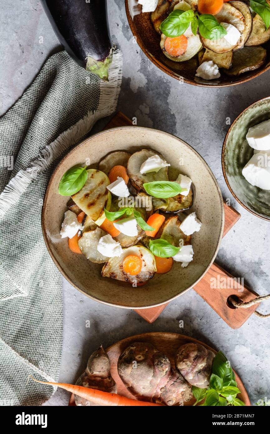 Grilled Jerusalem artichoke, eggplant, carrot, parsley root and kohlrabi  with goat cheese in a bowl Stock Photo - Alamy