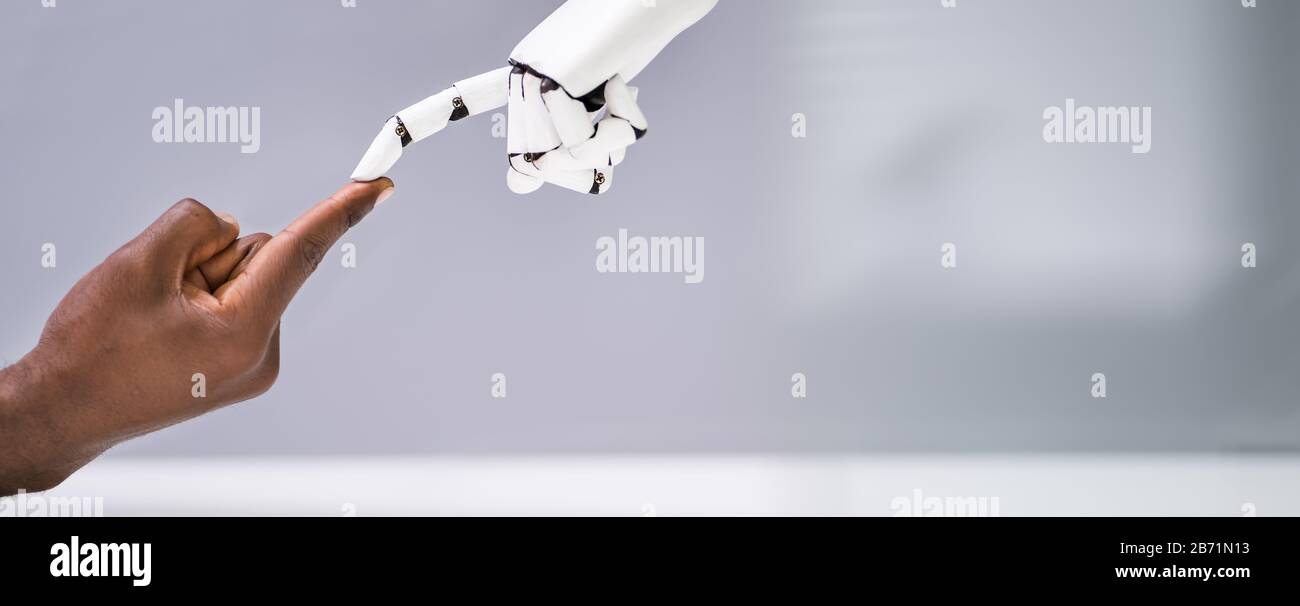 Robot Touching Human Finger Against Gray Background Stock Photo