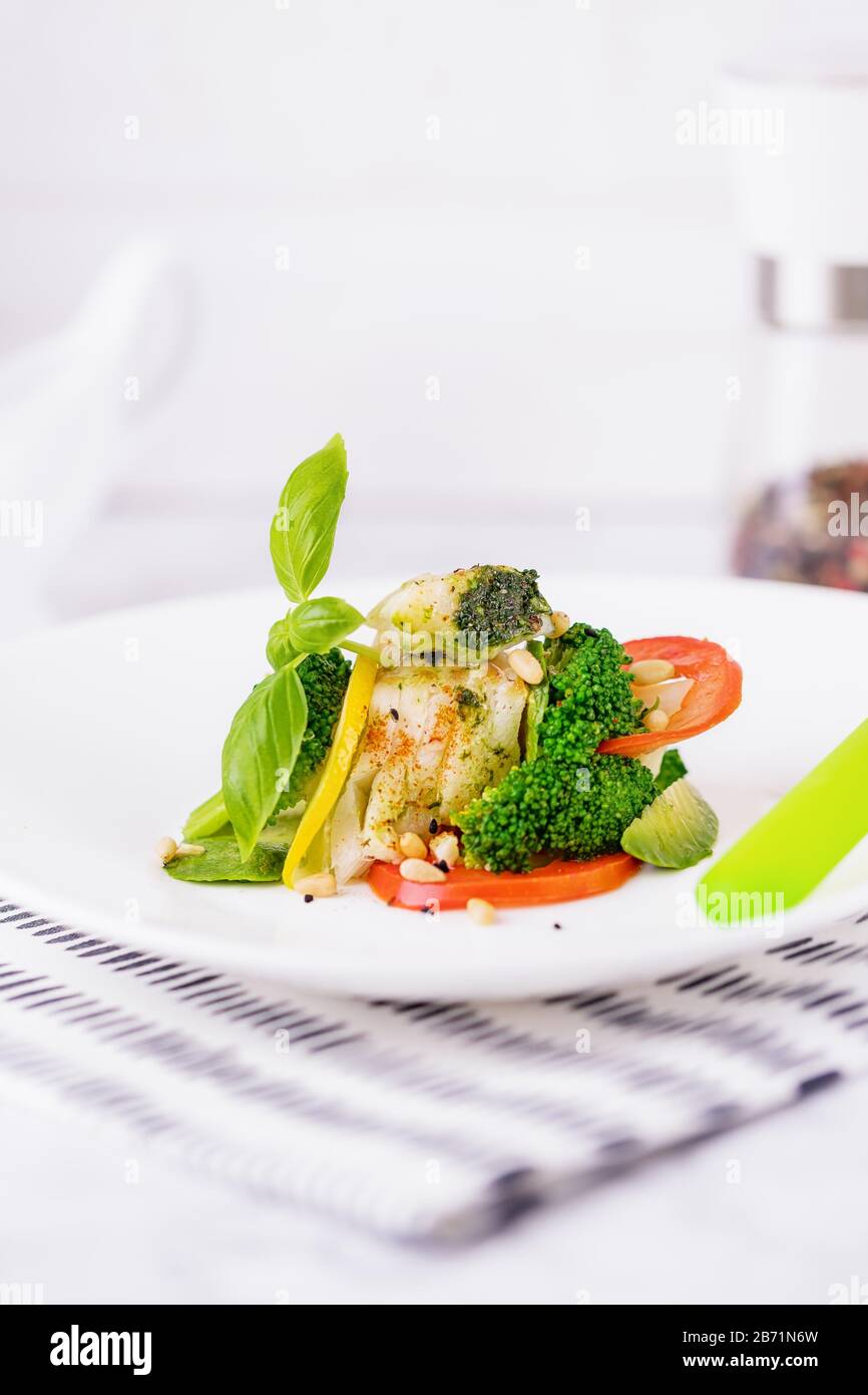 Steamed cod fish fillet with broccoli, tomato, lemon, avocado, basil