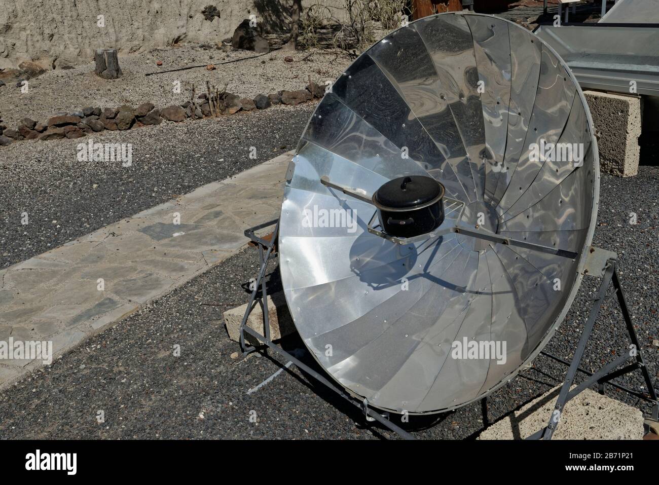 Solar cooker, with a reflective parabolic dish focusing heat from the sun onto a metal casserole pot, within a renewable energy display at ITER Biocli Stock Photo