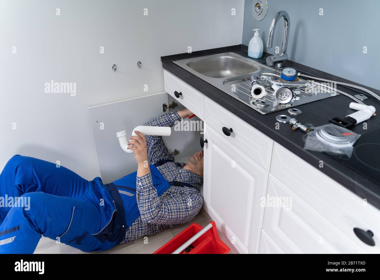 Male Plumber In Overall Fixing Kitchen Sink Pipe Stock Photo